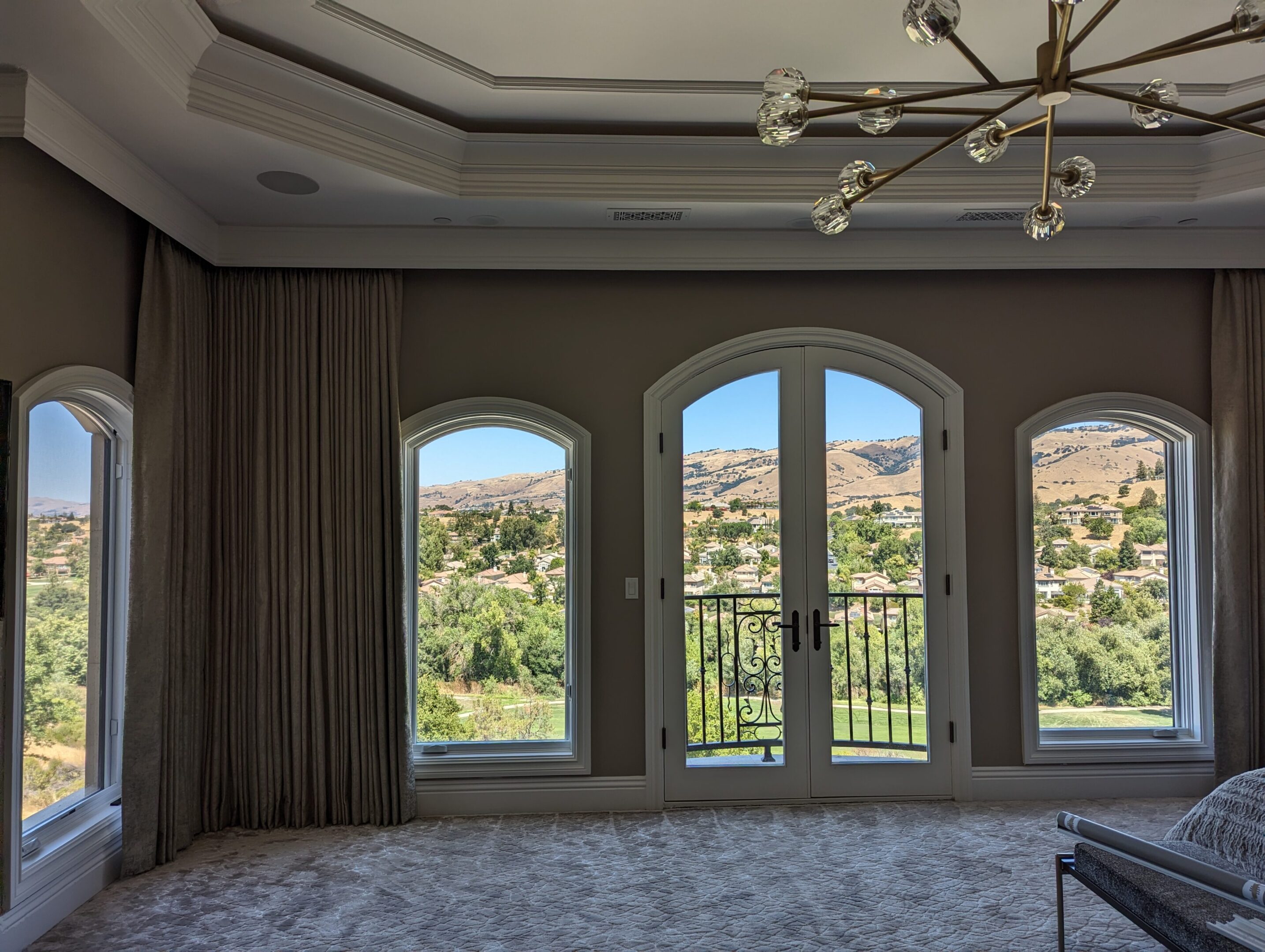 A room with two arched windows and a view of the mountains.