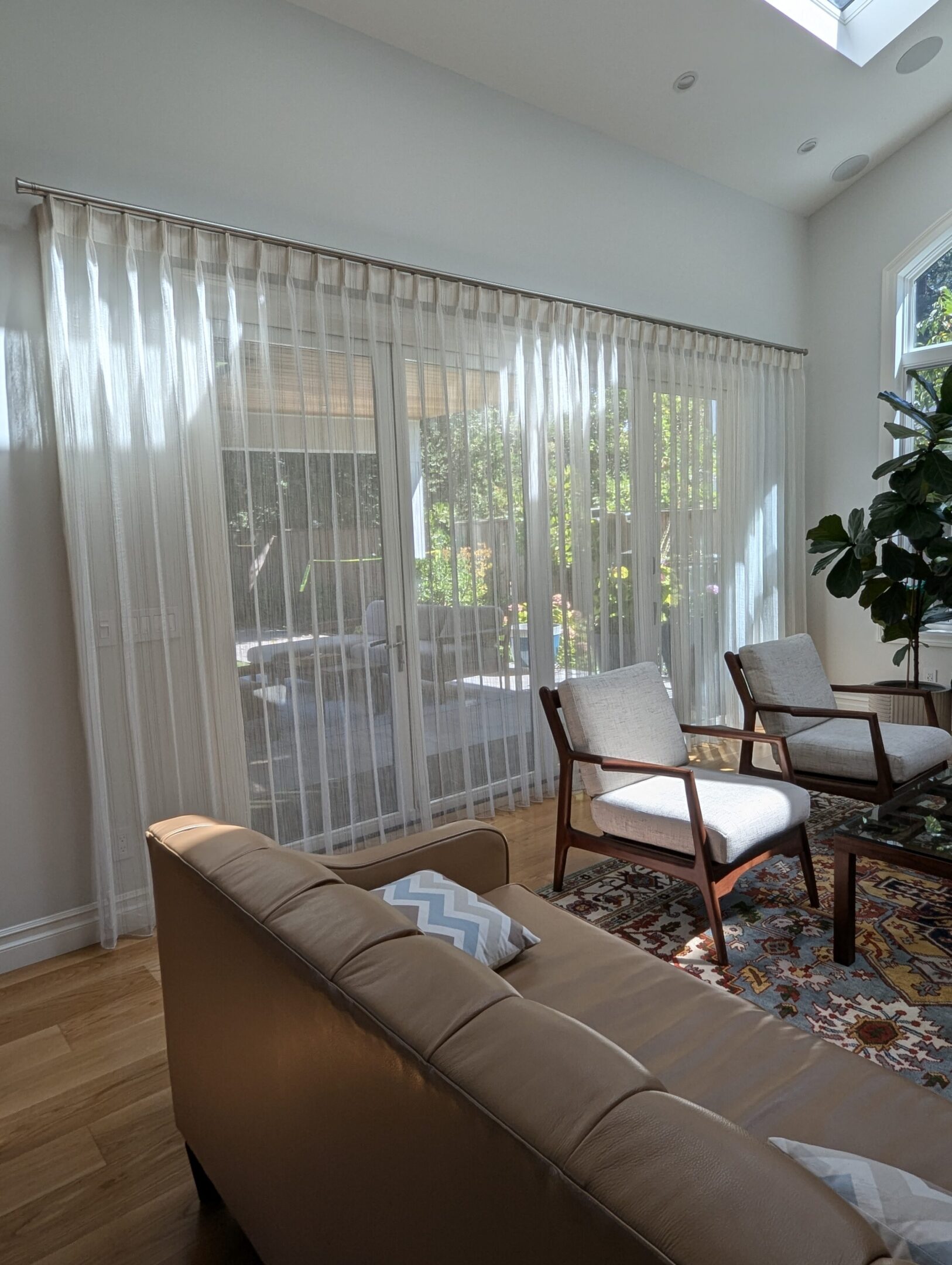 A living room with white curtains and brown furniture.