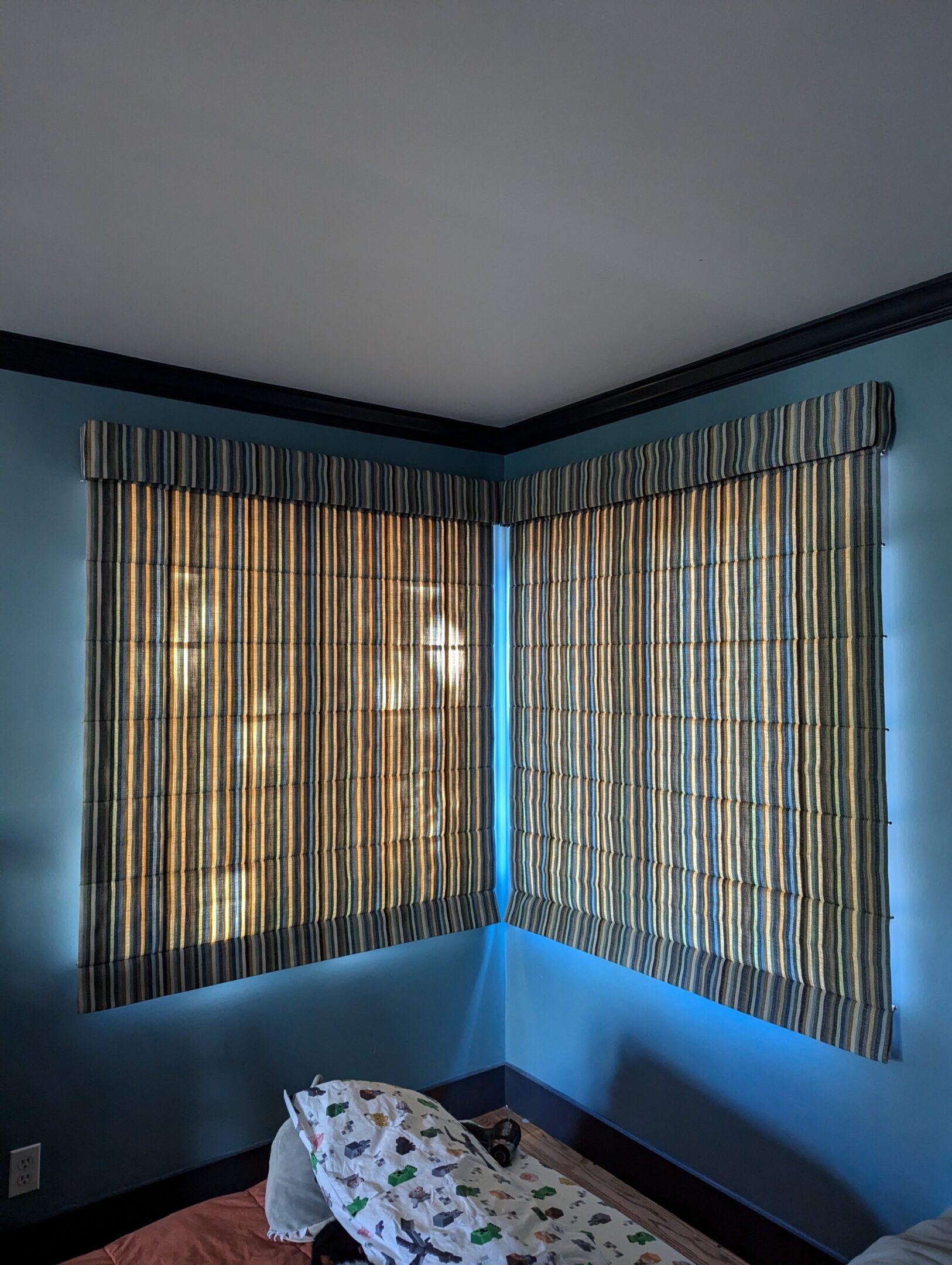 A corner window with blinds in the middle of it.