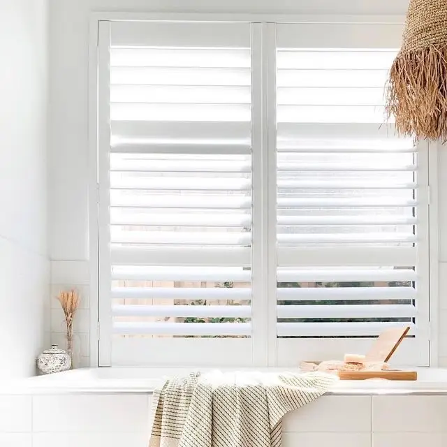 A bathroom with white walls and wooden shutters.