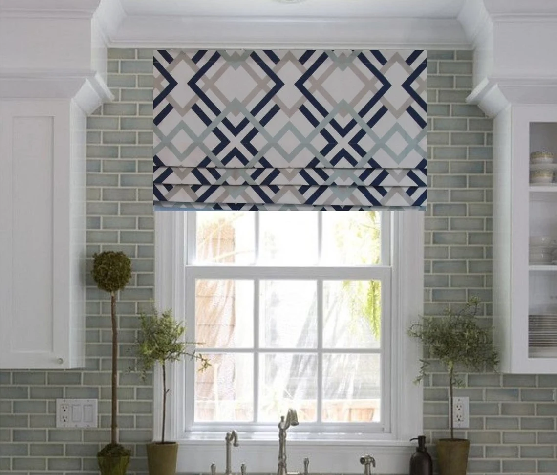 A kitchen window with roman shades and a sink.